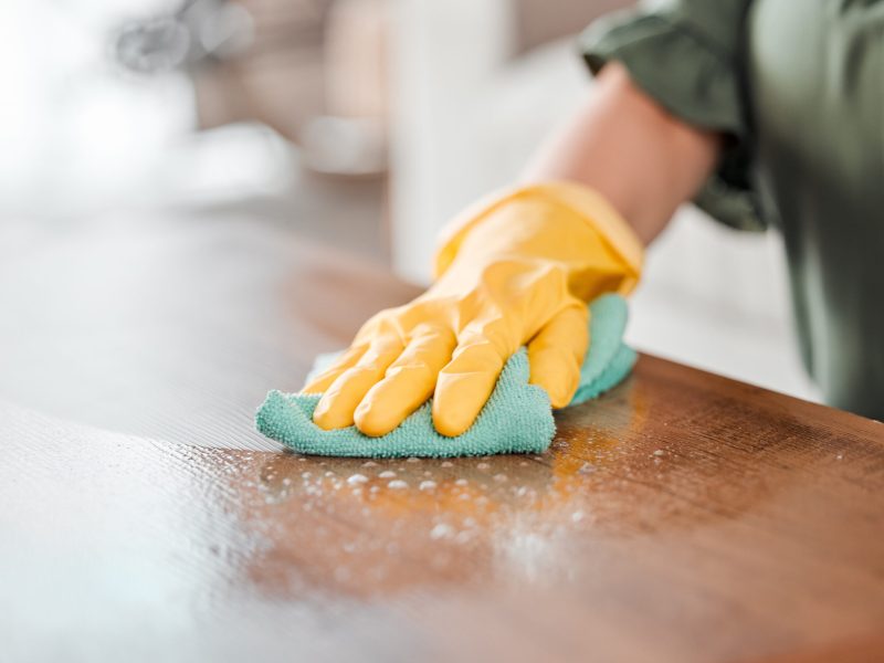 Hands, cleaning and bacteria on a wooden table for hygiene, disinfection or to sanitize a surface i.