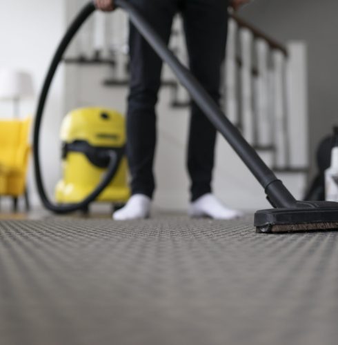 Man vacuuming the carpet in the room. House cleaning process